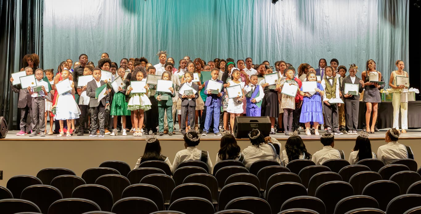 Students on stage holding the certificates they earned